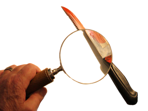 Das Bild zeigt ein blutiges Messer, das mit einer Lupe untersucht wird